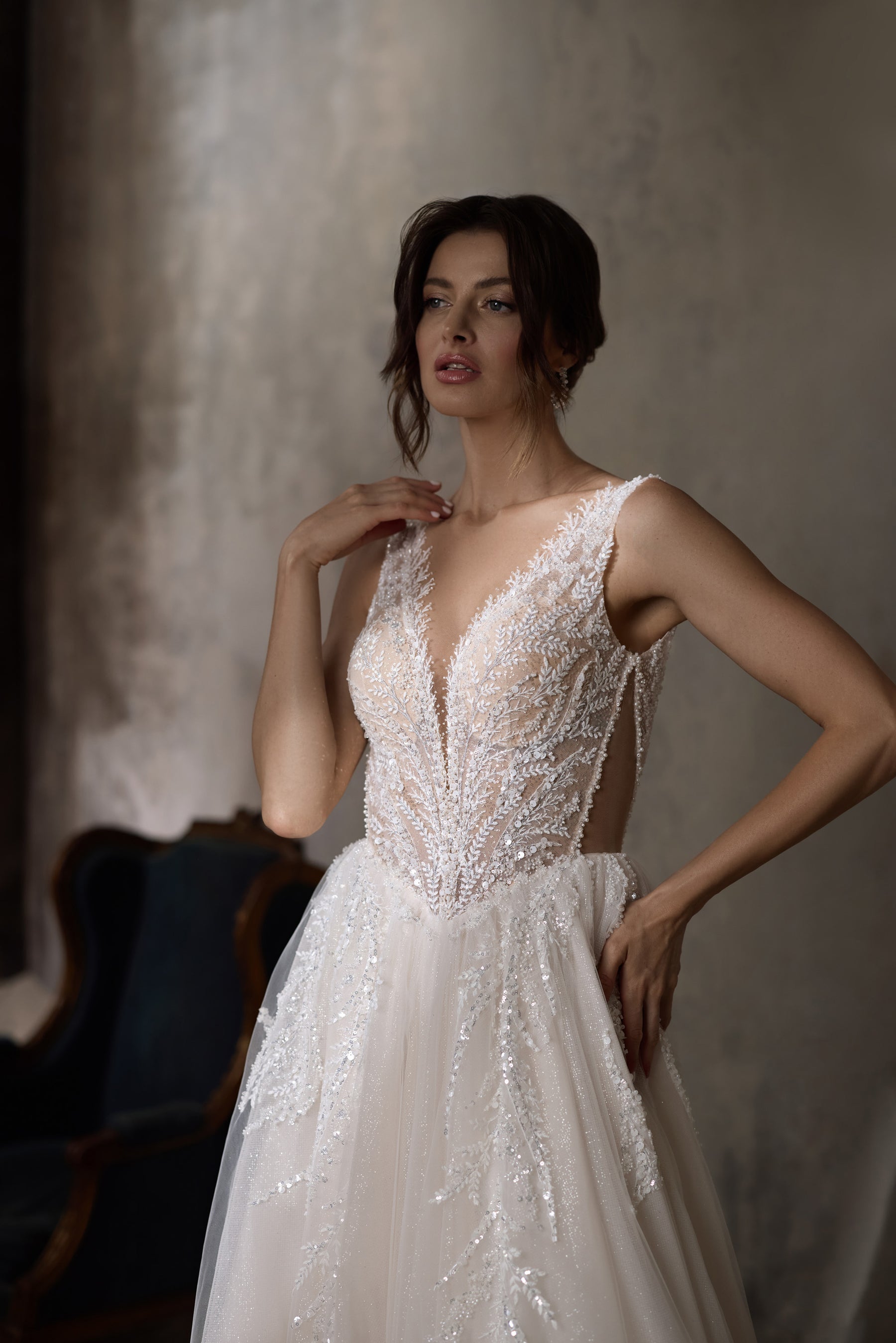 Ivory wedding dress with a plunging V-neck, sleeveless beaded lace bodice, and flowing A-line skirt