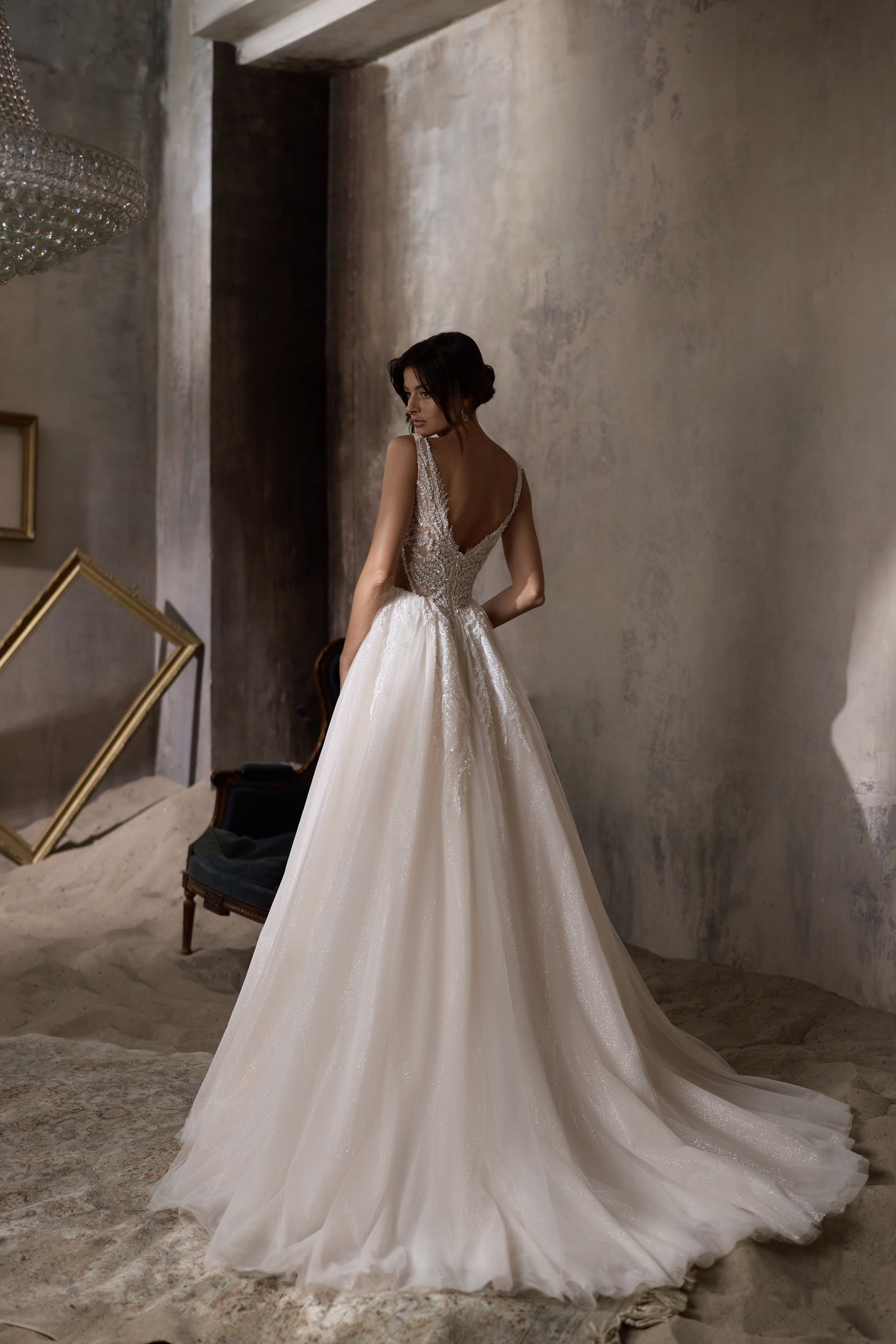 Open V-back wedding dress with lace detailing, a full A-line skirt, and a long sweeping train