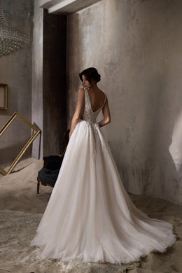 Open V-back wedding dress with lace detailing, a full A-line skirt, and a long sweeping train