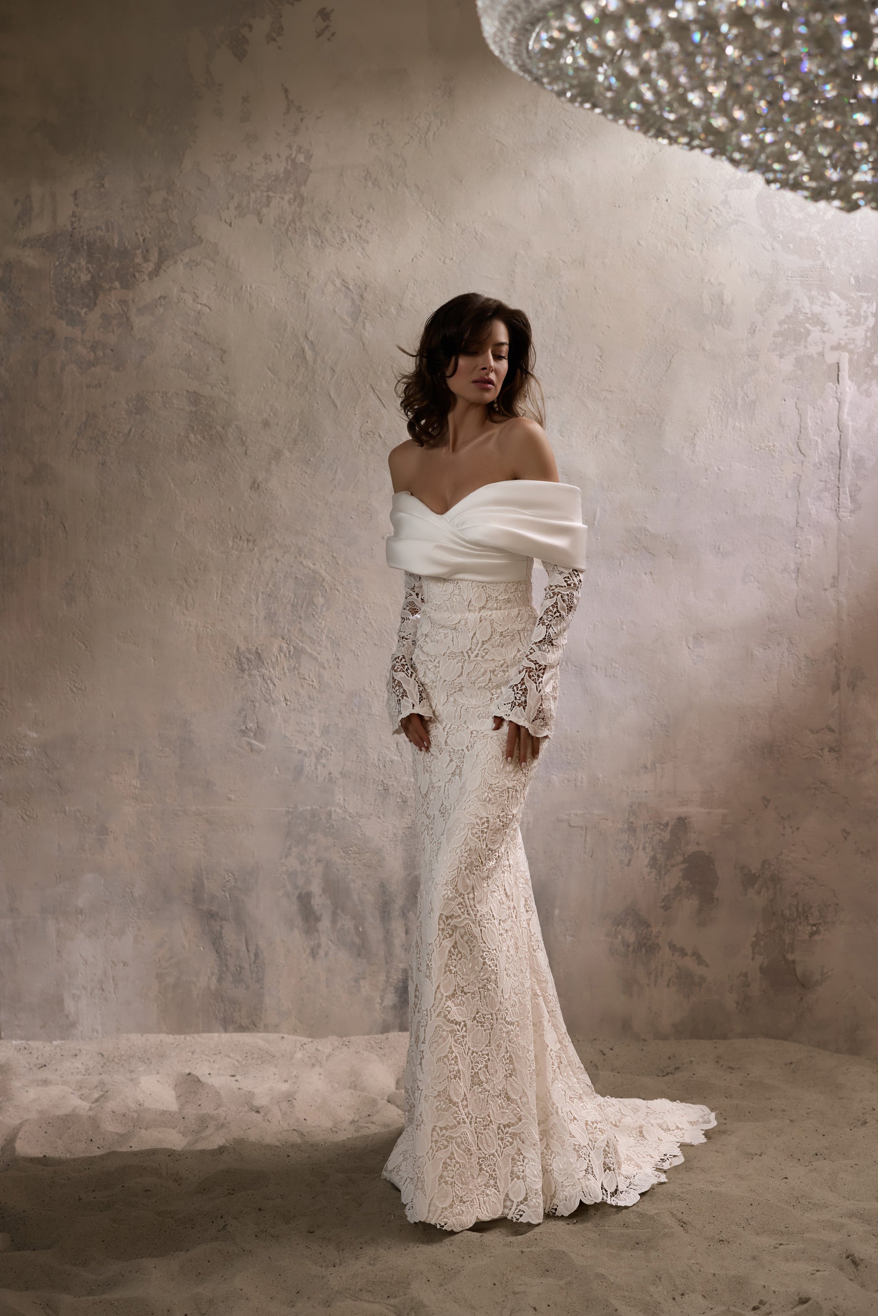 Ivory sheath wedding dress with an off-the-shoulder satin neckline, long lace sleeves, and a sweeping train