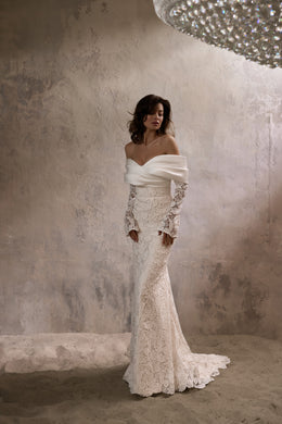 Ivory sheath wedding dress with an off-the-shoulder satin neckline, long lace sleeves, and a sweeping train