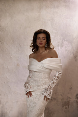 Close-up of an ivory wedding dress bodice with a draped off-the-shoulder satin neckline and floral lace sleeves