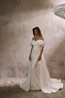 Ivory lace wedding dress with an off-the-shoulder satin neckline and a flowing floor-length overskirt
