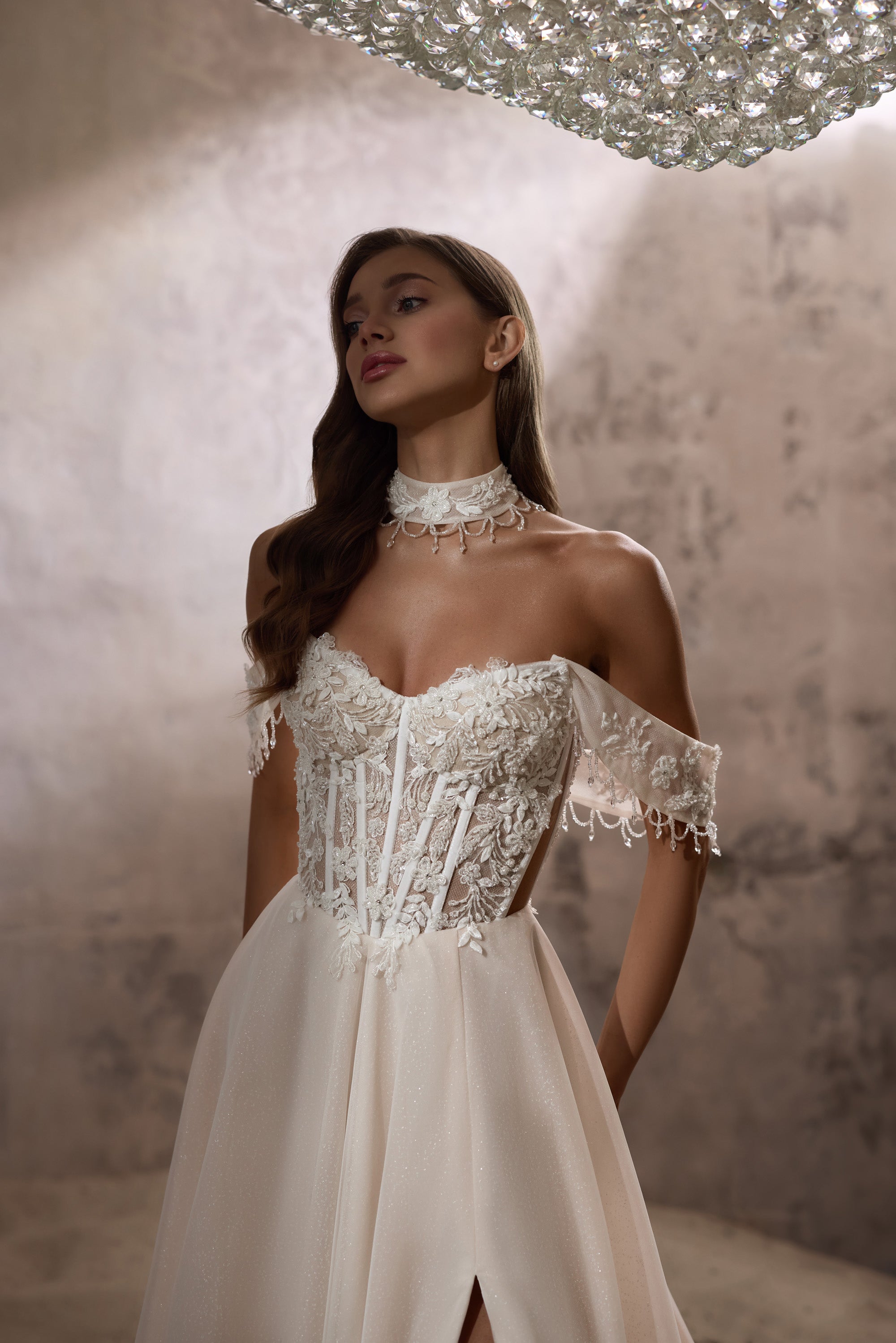 Ivory A-line wedding dress with a floral beaded corset, off-shoulder wrap, and front slit