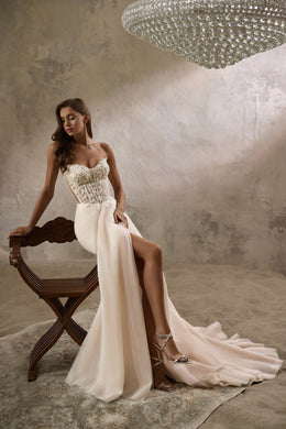 Ivory wedding dress with an embellished corset bodice, high front slit, and flowing train