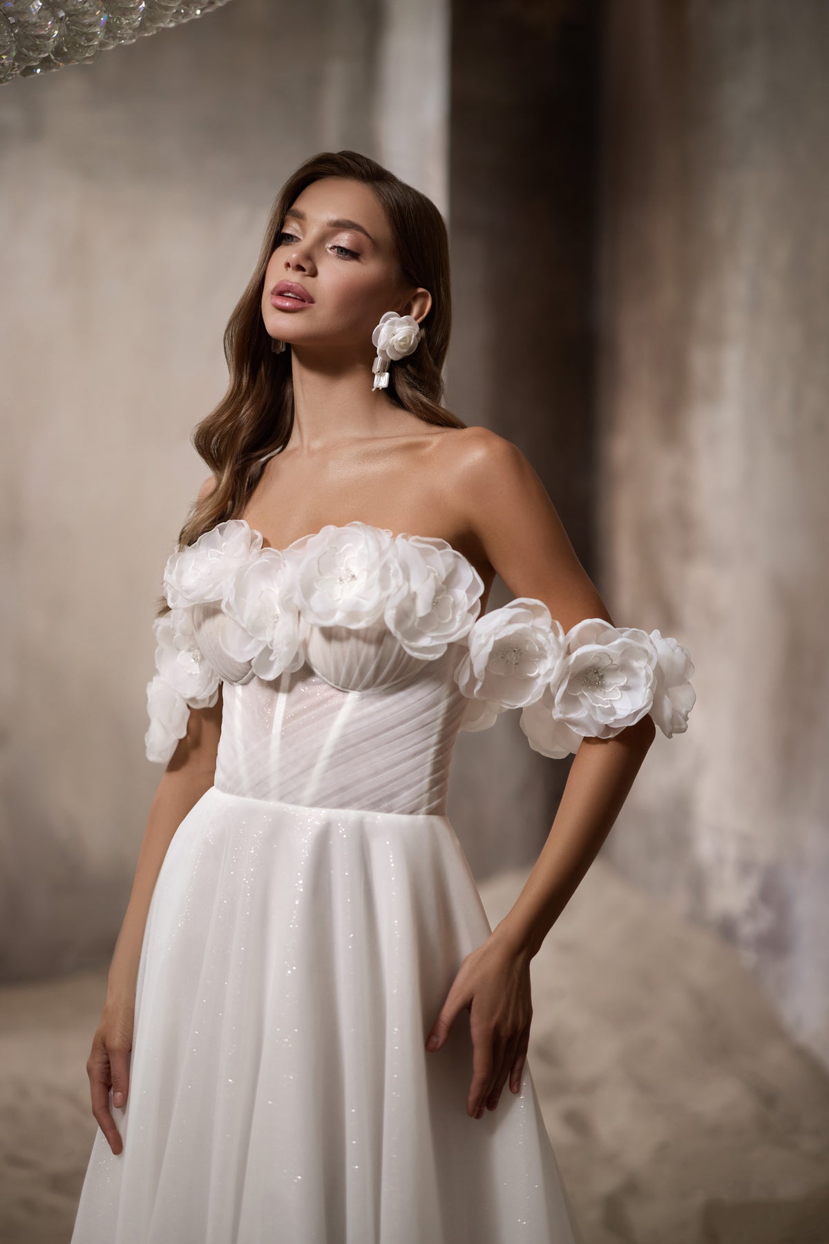 Ivory A-line wedding dress with a ruched bodice, off-the-shoulder 3D floral trim, and glittering skirt