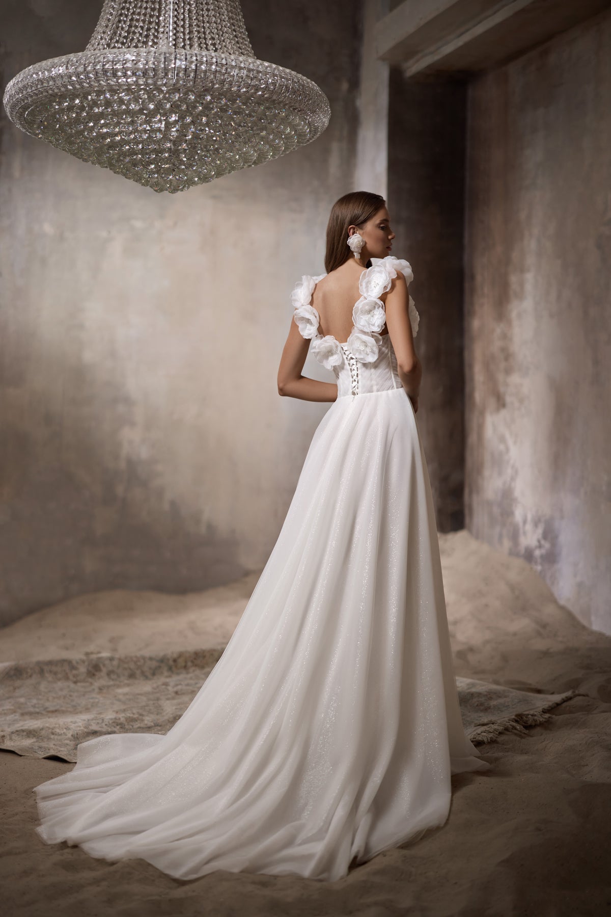 Open-back ivory wedding dress with 3D floral shoulder details, a flowing A-line skirt, and long train