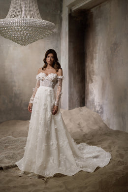 Ivory wedding dress with a beaded floral overskirt, off-the-shoulder sleeves, and long scalloped train