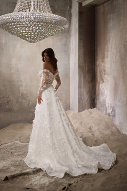 Ivory wedding dress with a full floral overskirt, fitted bodice, and long scalloped train shown from the side