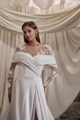 Close-up of an ivory wedding dress with sheer floral lace sleeves and a draped neckline