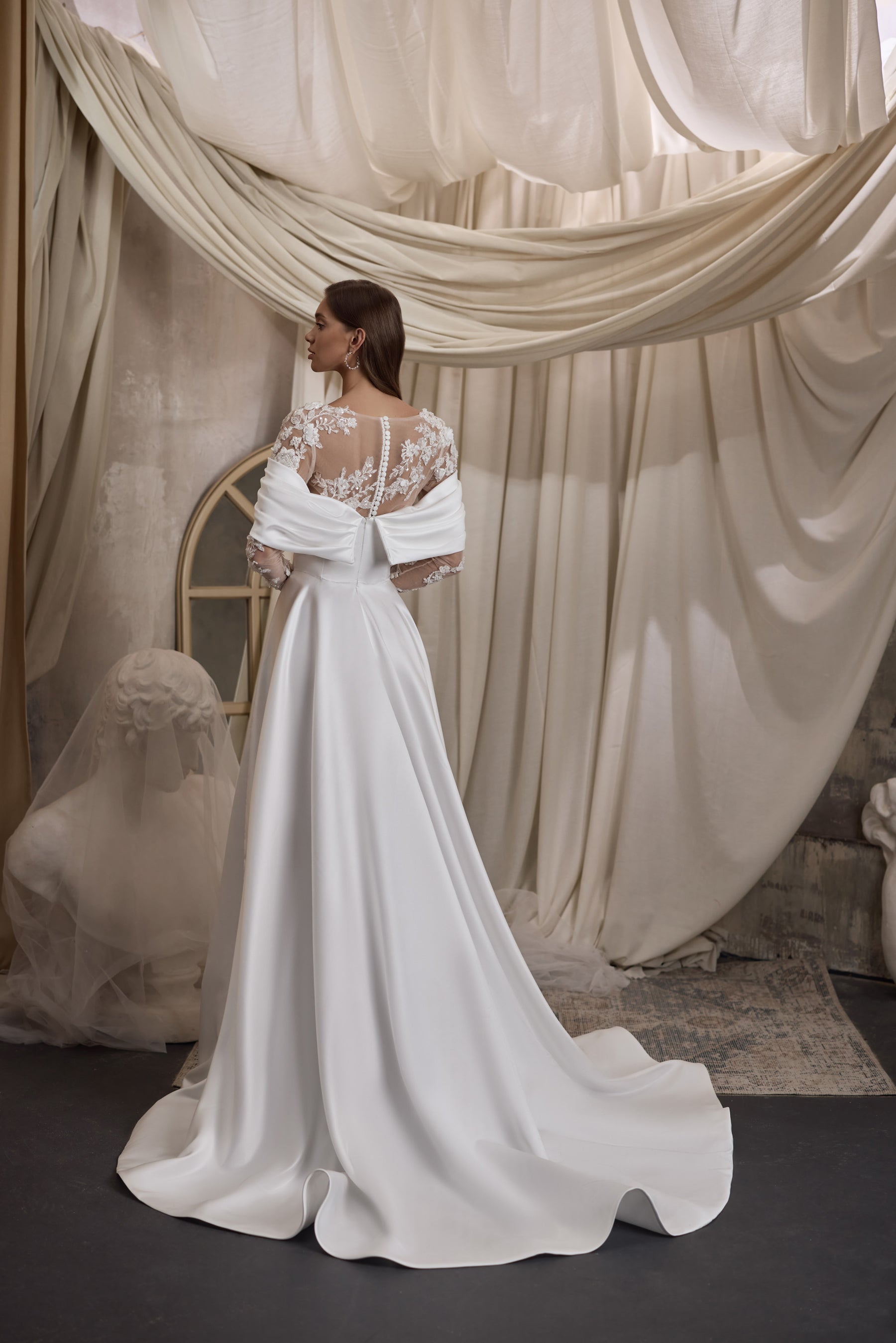 Ivory wedding dress with a sheer floral lace back, draped sleeves, and a long flowing train