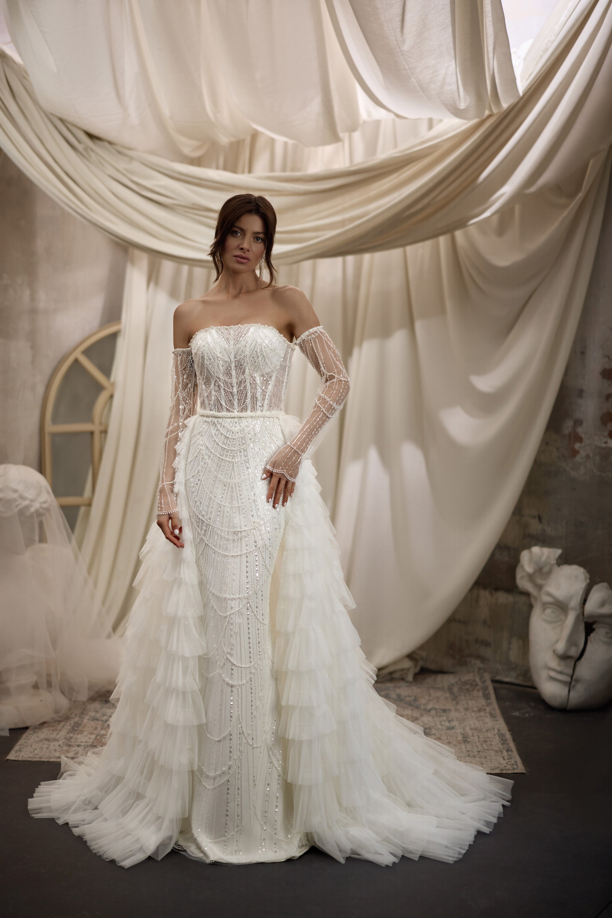 Ivory beaded wedding dress with sheer embellished sleeves and a layered ruffle overskirt