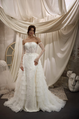 Ivory beaded wedding dress with sheer embellished sleeves and a layered ruffle overskirt