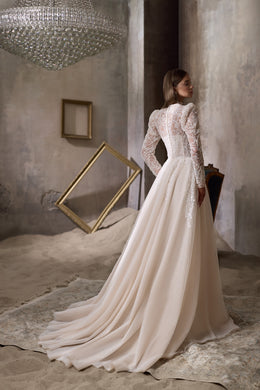Ivory wedding dress showing a lace-covered back, long sleeves, and a flowing train