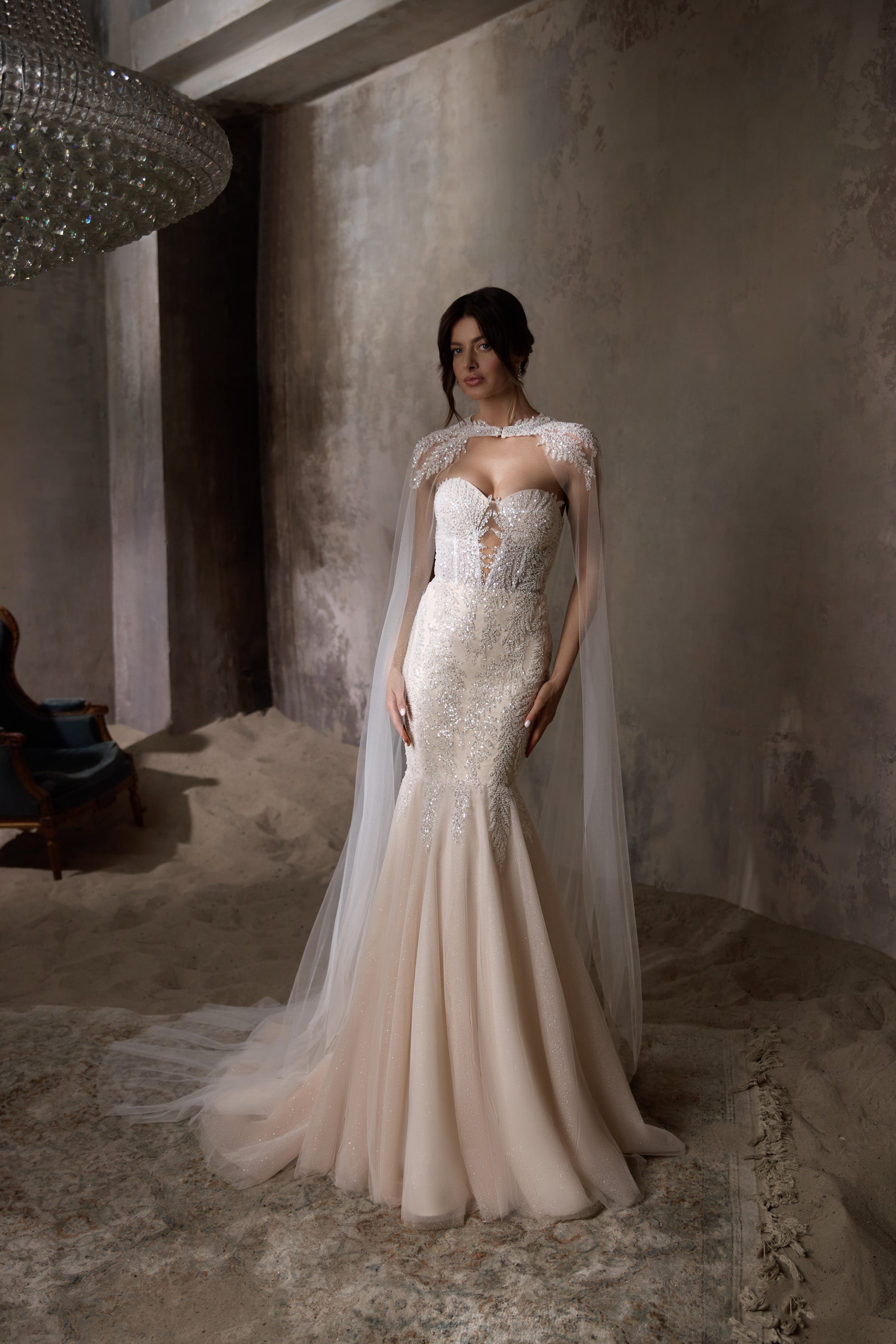 Beaded ivory mermaid wedding dress with a sheer embellished cape and fitted sweetheart bodice