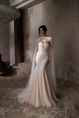Beaded ivory mermaid wedding dress with a sheer embellished cape and fitted sweetheart bodice