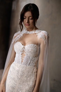 Close-up of a beaded sweetheart bodice and sheer floral-embellished cape on a wedding dress