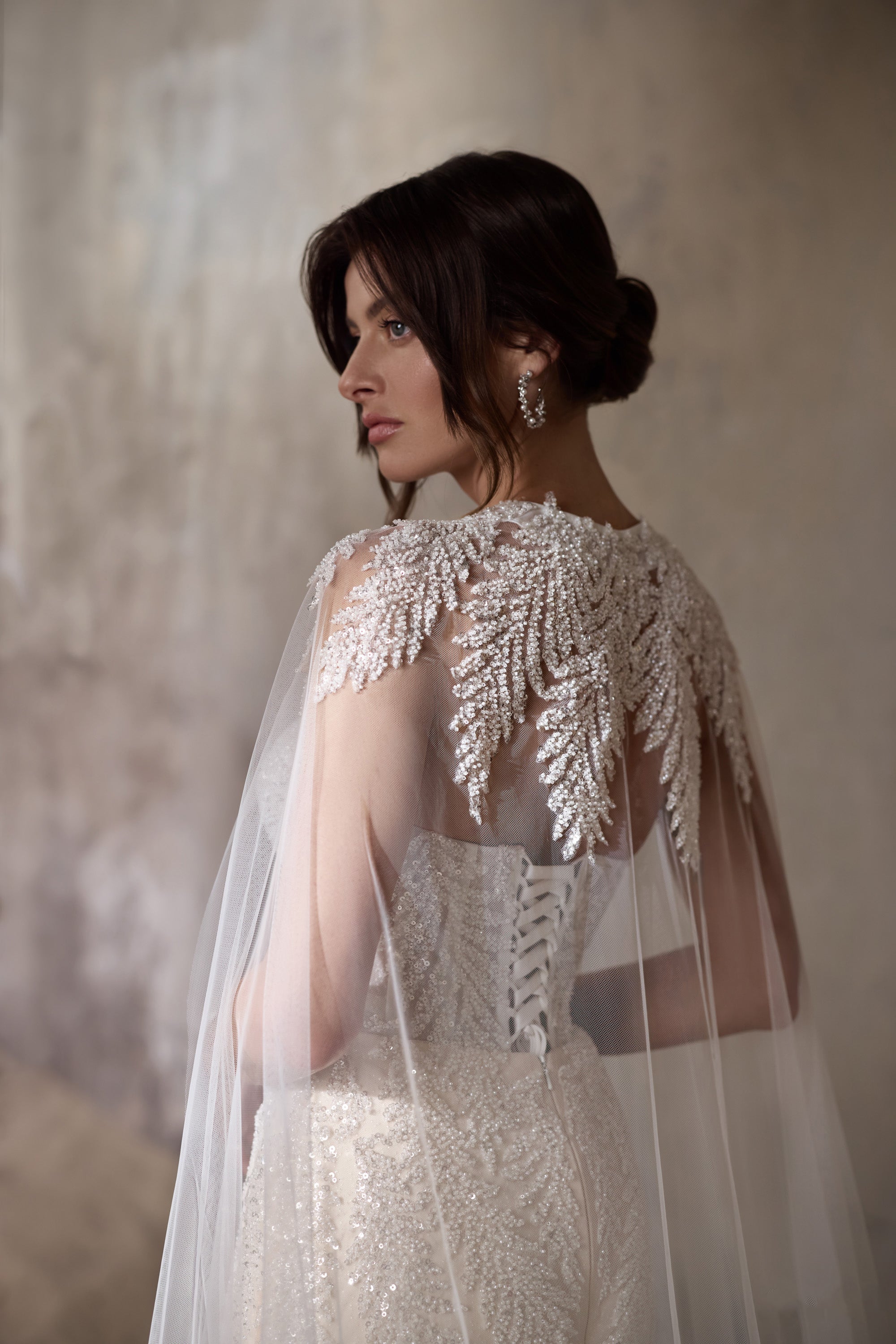 Embellished sheer cape over the beaded back of an ivory mermaid wedding dress