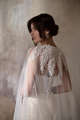 Embellished sheer cape over the beaded back of an ivory mermaid wedding dress
