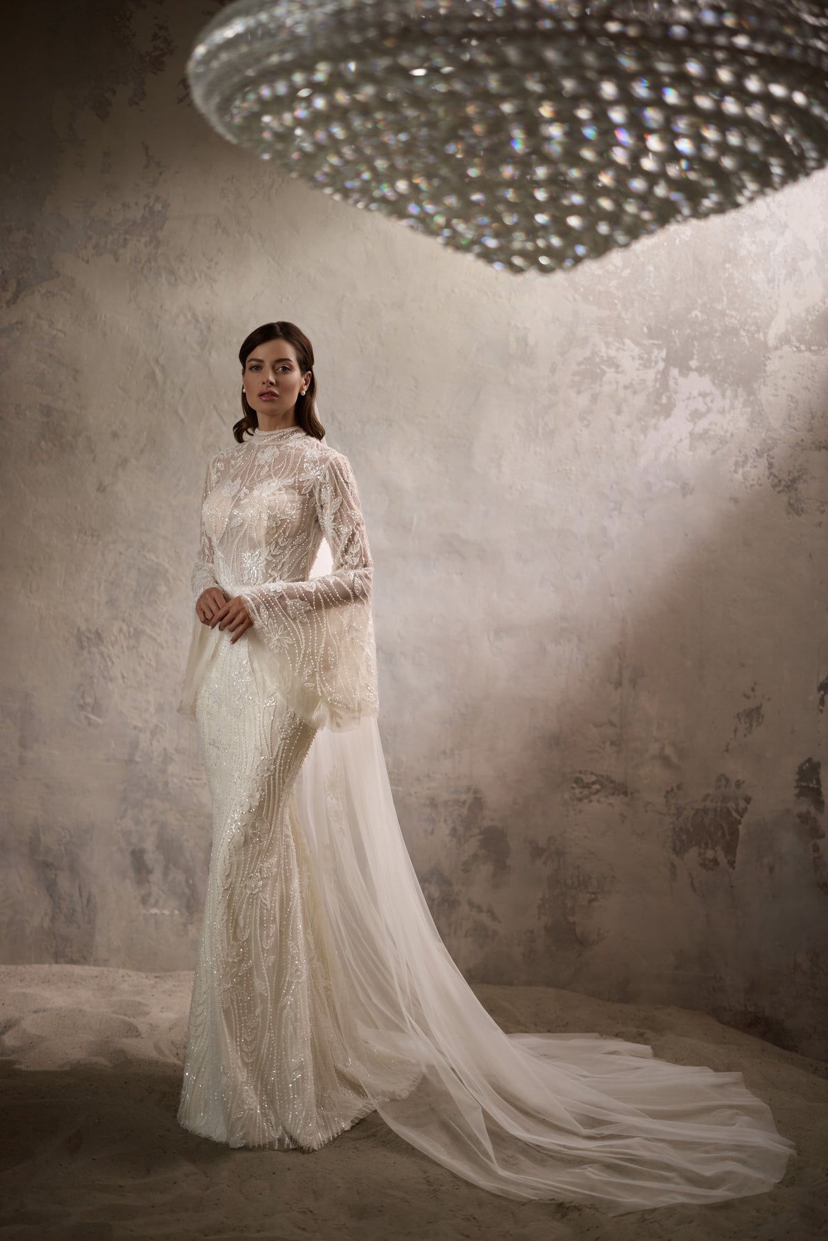 Ivory wedding dress with a beaded high-neck bodice, long sleeves, fitted silhouette, and sweeping train