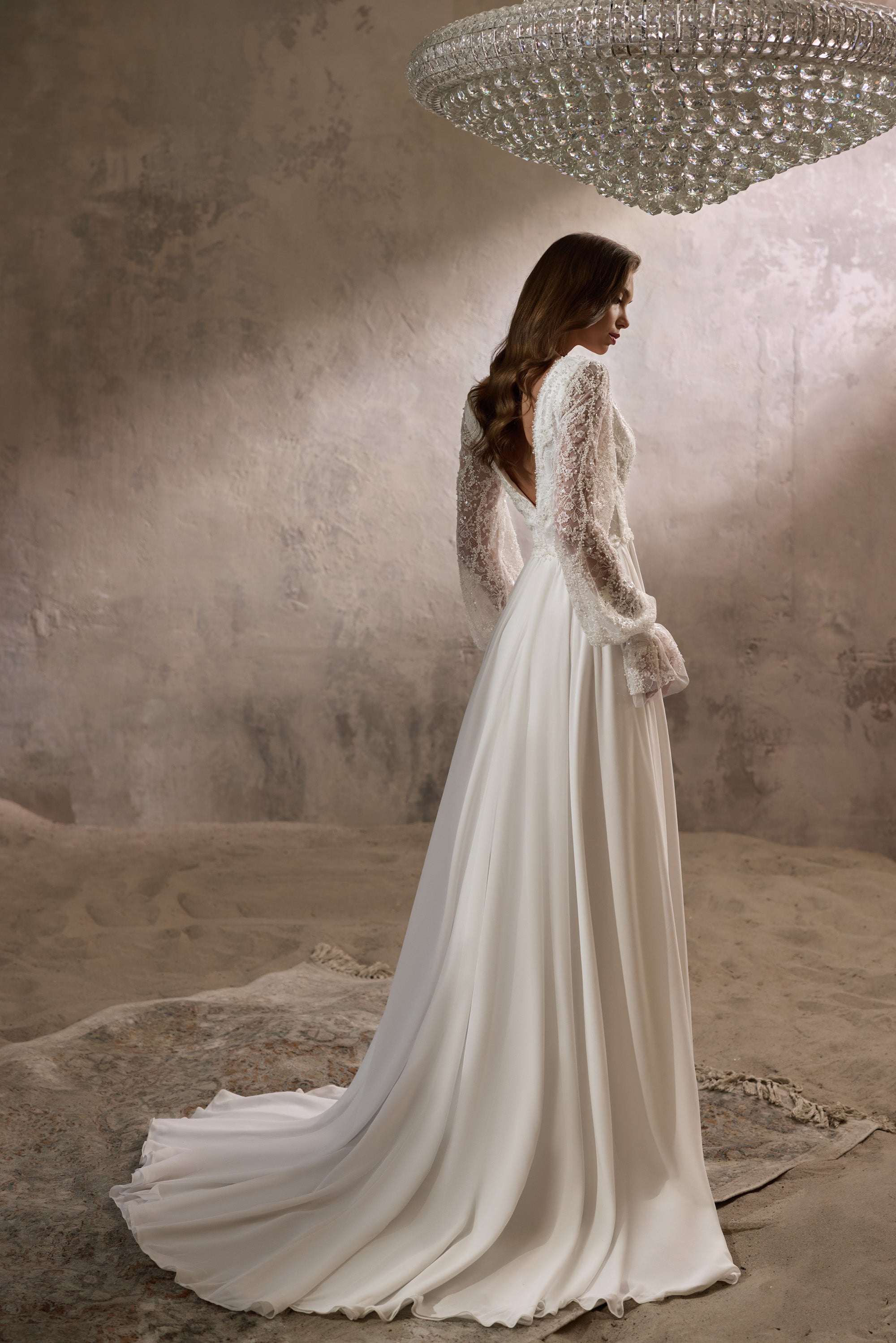 Ivory wedding dress with sheer lace long sleeves, flowing A-line skirt, and extended train shown from behind