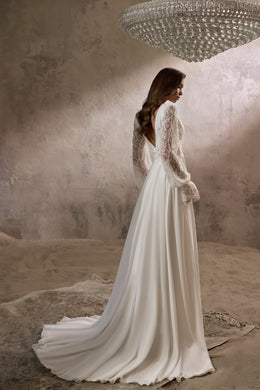 Ivory wedding dress with sheer lace long sleeves, flowing A-line skirt, and extended train shown from behind