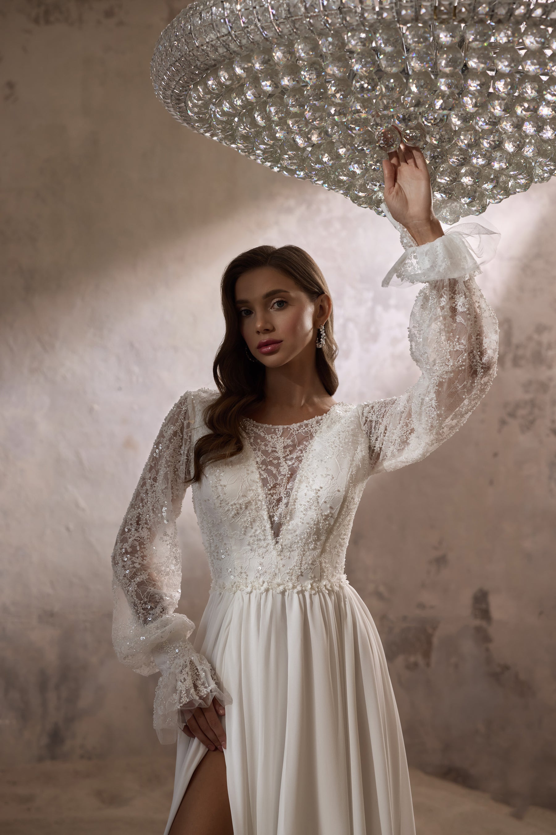 Close-up of an ivory wedding dress with beaded lace bodice, illusion V-neckline, and sheer ruffled sleeves