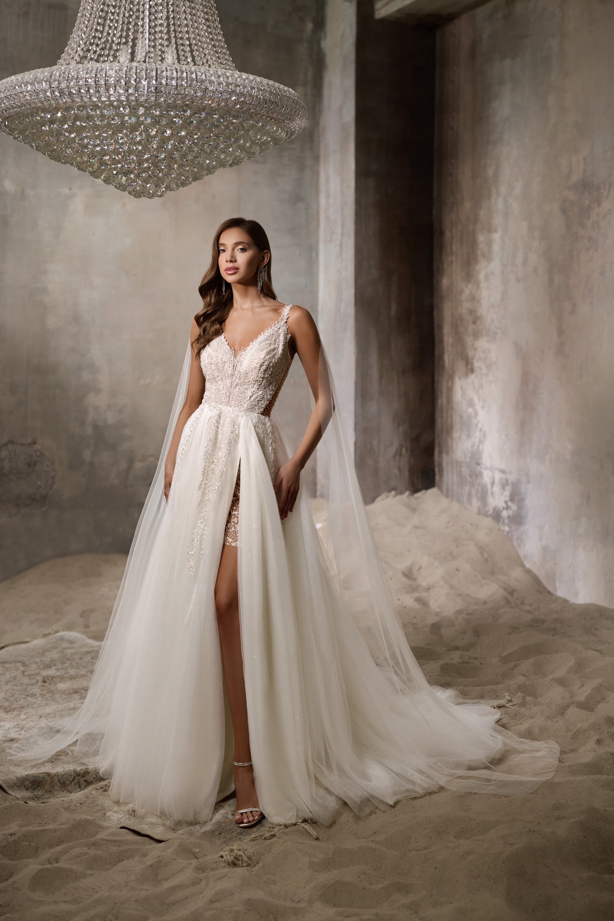 Ivory wedding dress with beaded V-neck bodice, thin straps, high front slit, and flowing overskirt