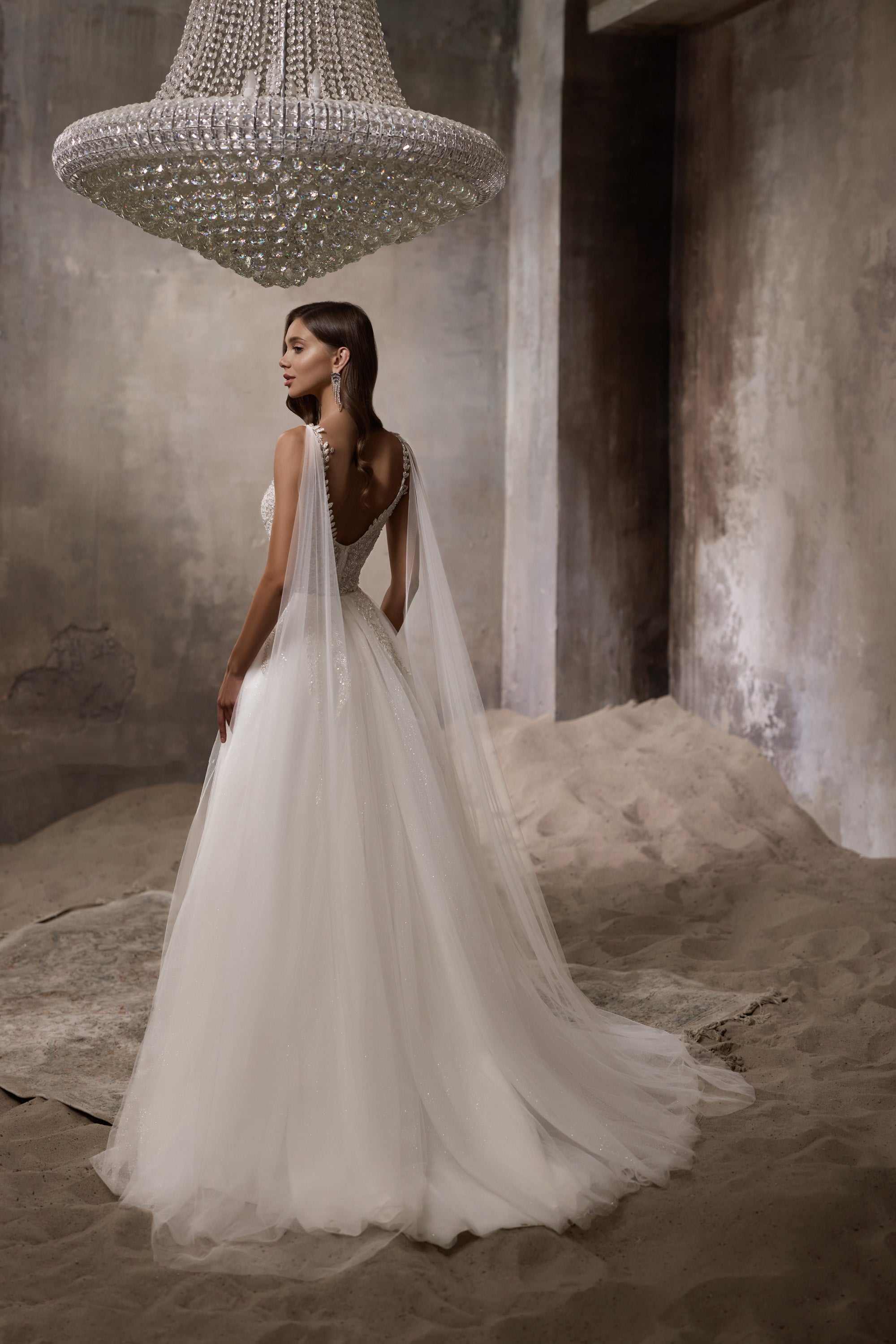 Open low back and long flowing train on an ivory wedding dress, shown from behind