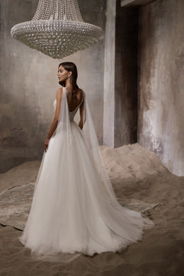 Open low back and long flowing train on an ivory wedding dress, shown from behind
