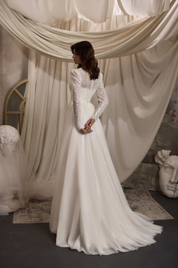 Ivory A-line wedding dress with sheer beaded lace long sleeves, high neck, and flowing train shown from behind