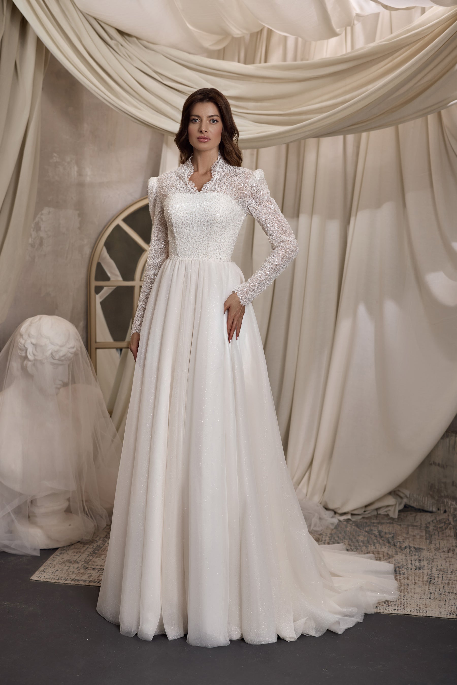 Ivory A-line wedding dress with a high neckline, long beaded lace sleeves, fitted bodice, and softly gathered skirt