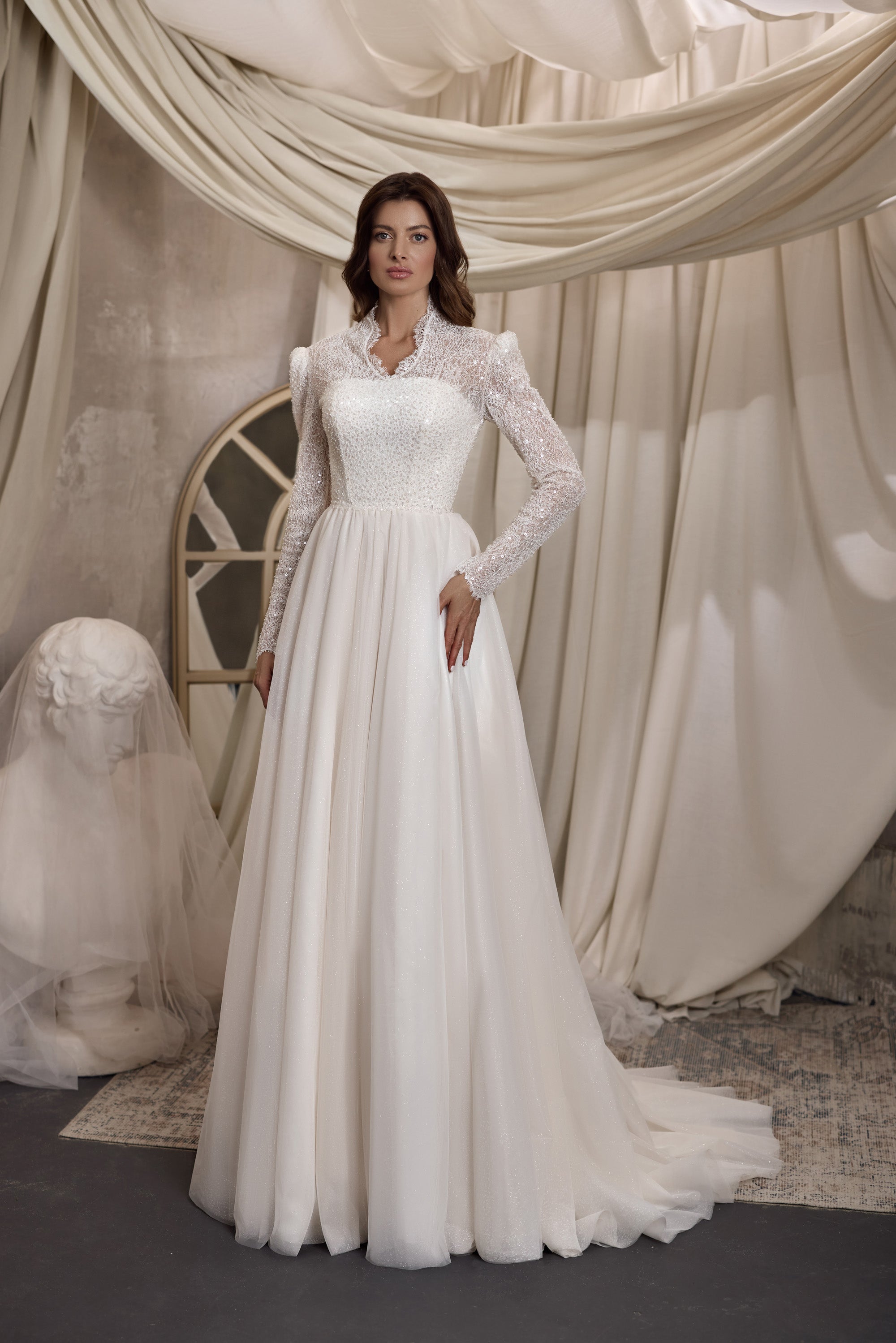 Ivory A-line wedding dress with a high neckline, long beaded lace sleeves, fitted bodice, and softly gathered skirt