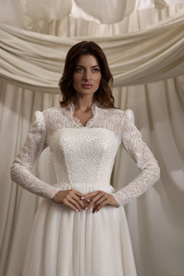 Close-up of the beaded lace high neckline, long sleeves, and fitted bodice on an ivory wedding dress