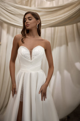 White wedding dress with a beaded sweetheart bodice, sheer center detail, and high thigh slit