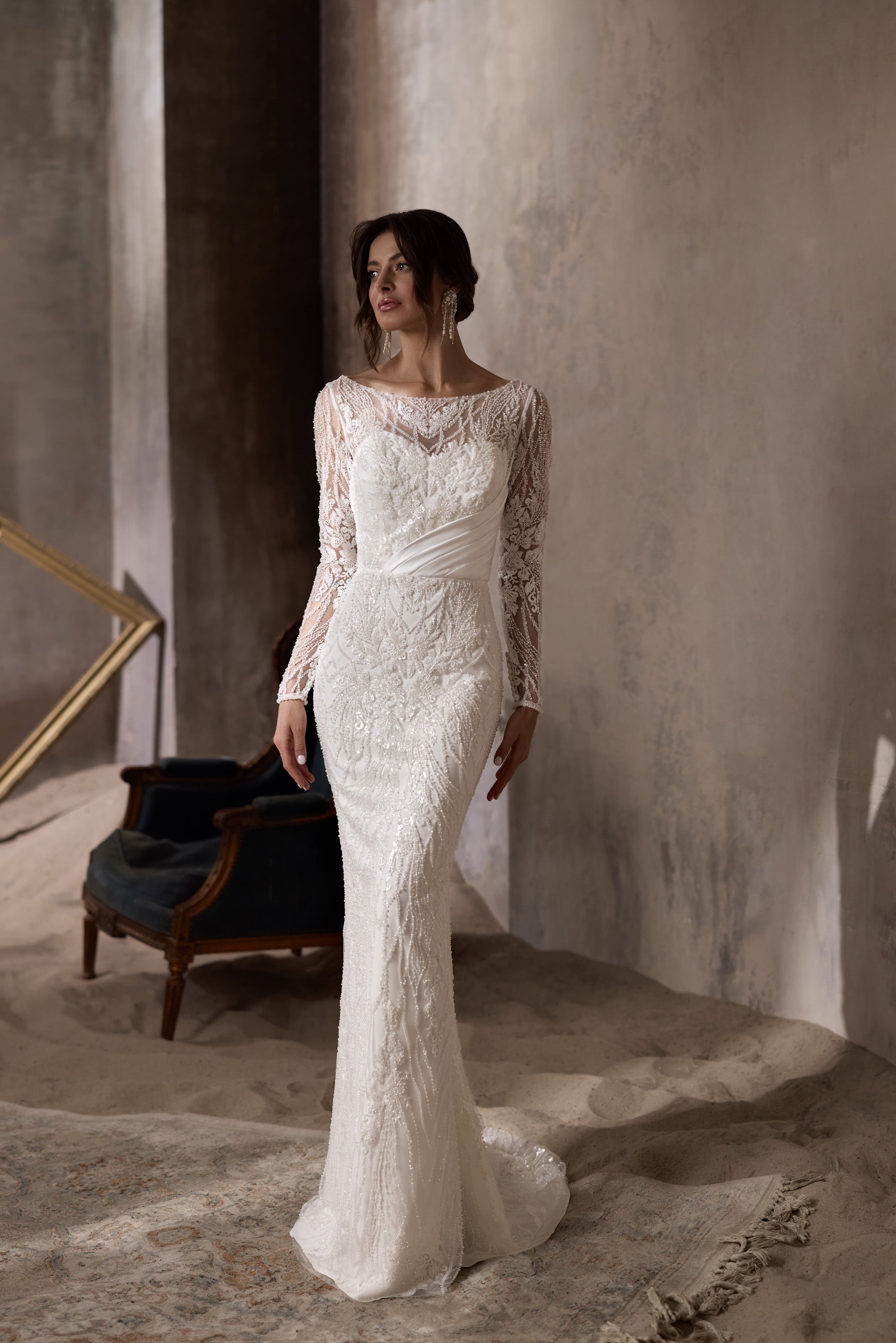 Ivory sheath wedding dress with a bateau neckline, long illusion lace sleeves, and a sweeping train