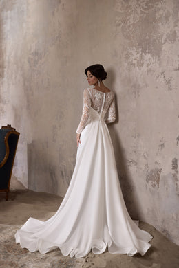 Back of an ivory wedding dress with a lace bodice, long sleeves, and a detachable flowing overskirt