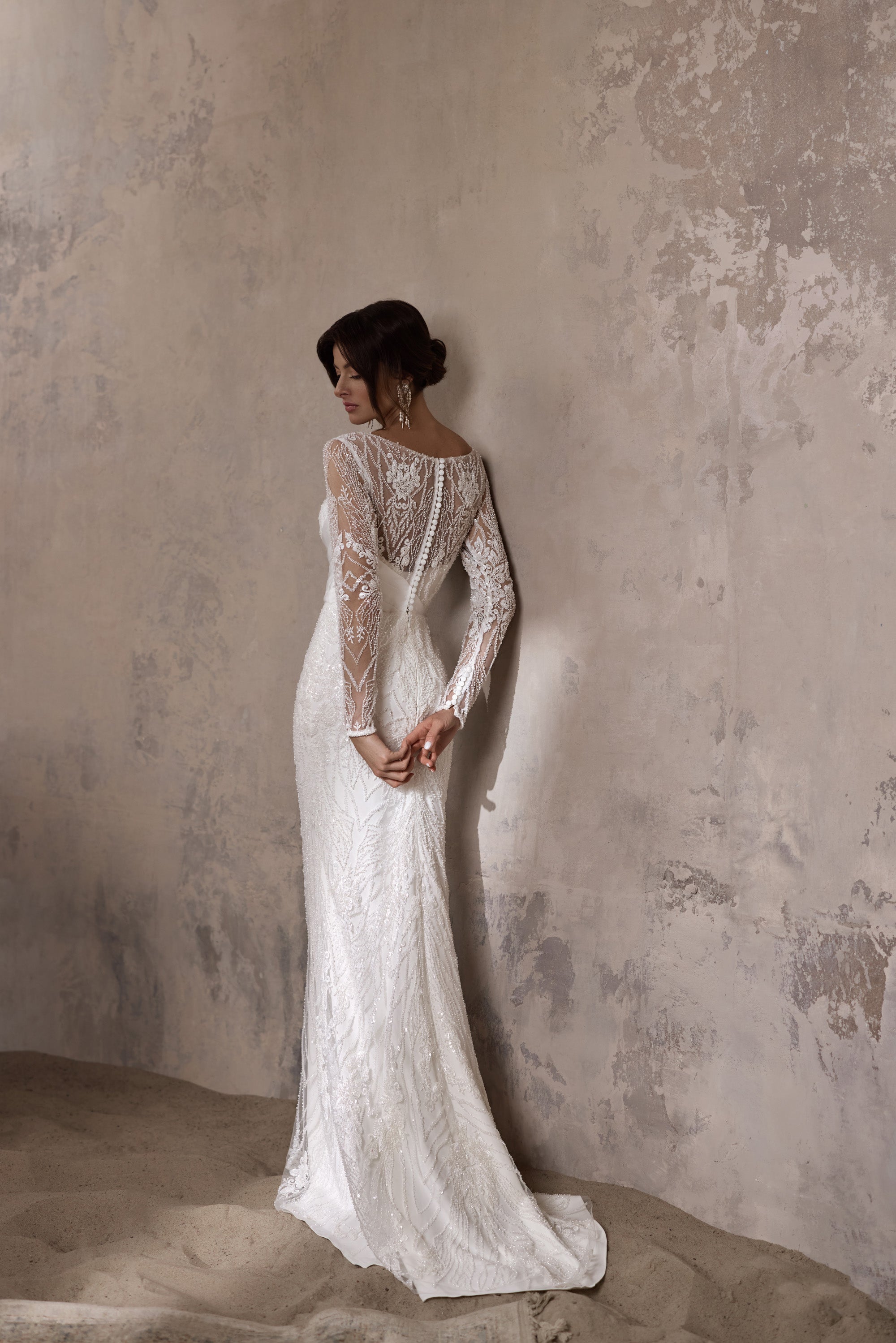 Ivory lace wedding dress with a fitted silhouette, sheer long sleeves, and a train, shown from the back
