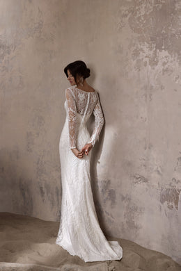 Ivory lace wedding dress with a fitted silhouette, sheer long sleeves, and a train, shown from the back
