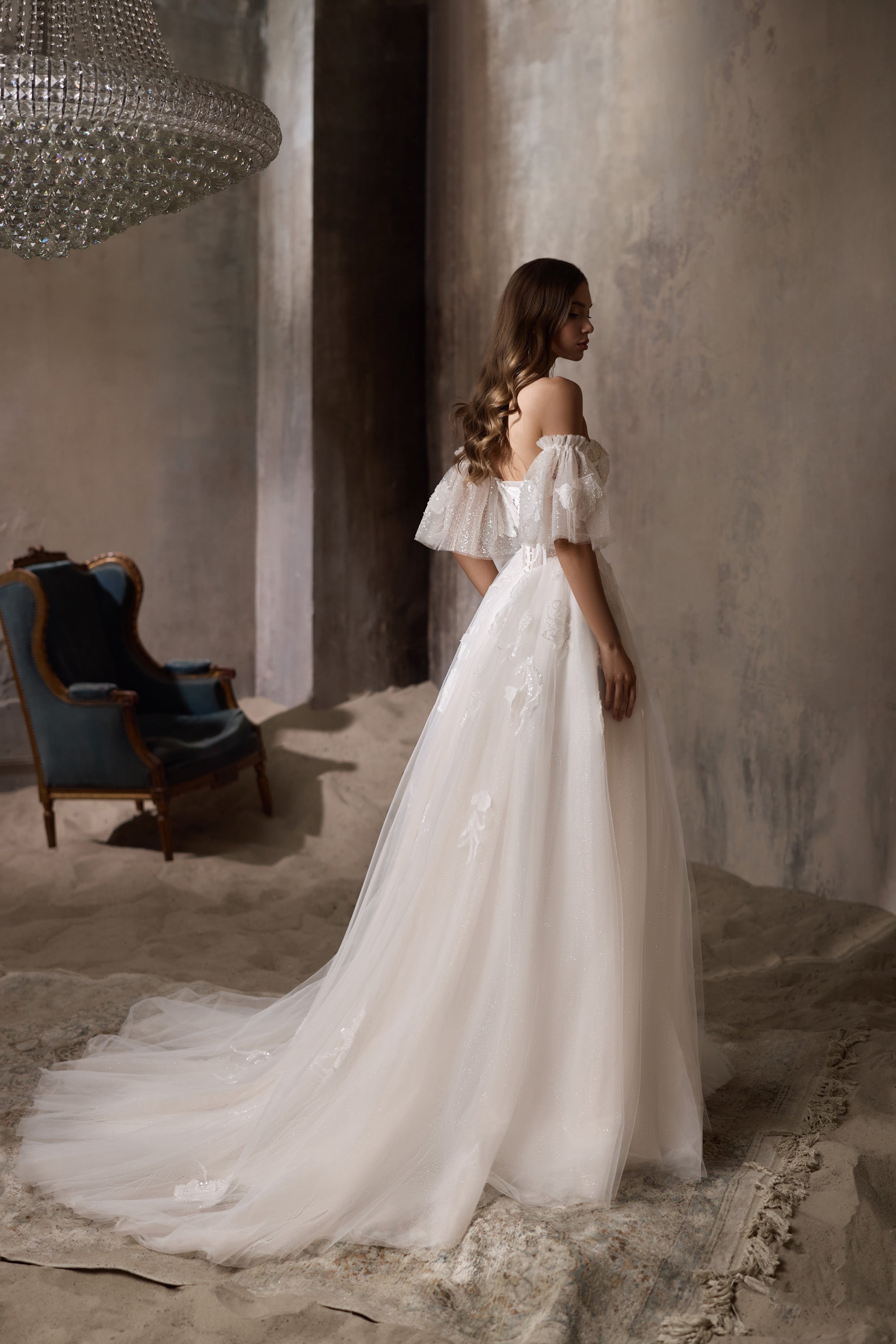 Ivory wedding dress with sheer puff sleeves, a flowing train, and glittering floral details