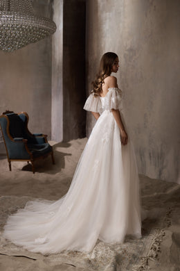Ivory wedding dress with sheer puff sleeves, a flowing train, and glittering floral details