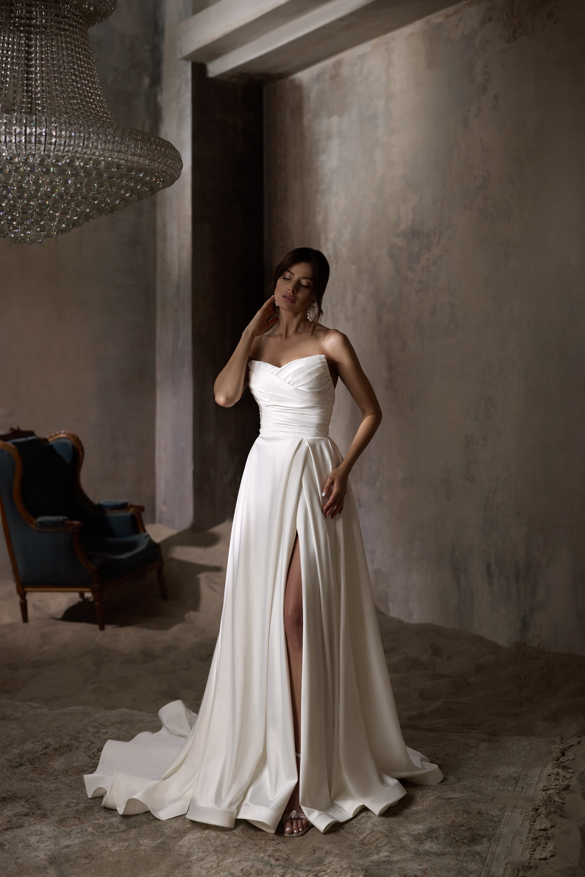 Strapless ivory wedding dress with a draped A-line skirt, high front slit, and long train