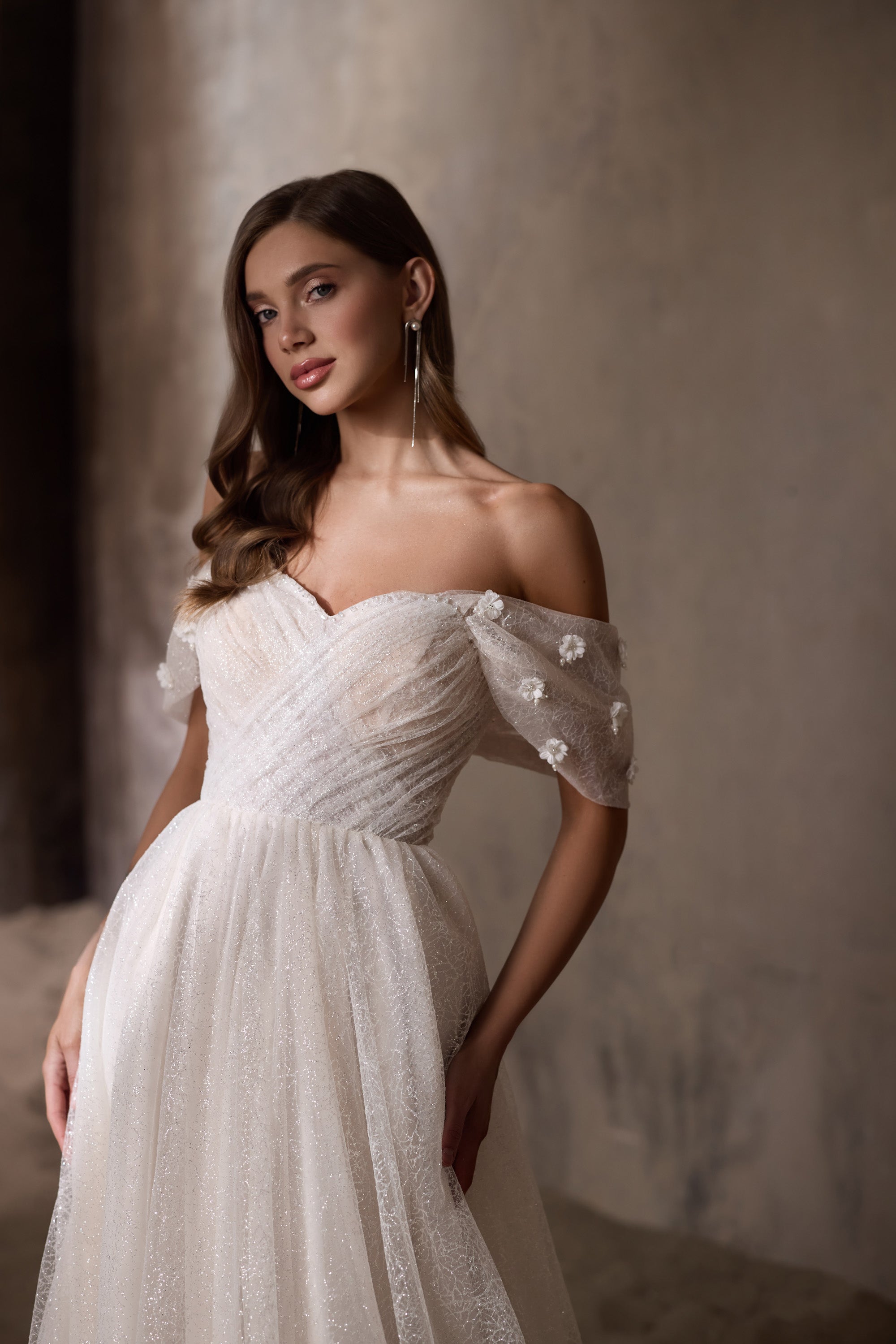 Close-up of an ivory wedding dress with a ruched sweetheart bodice and sheer floral-appliqué sleeves