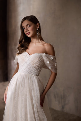 Close-up of an ivory wedding dress with a ruched sweetheart bodice and sheer floral-appliqué sleeves