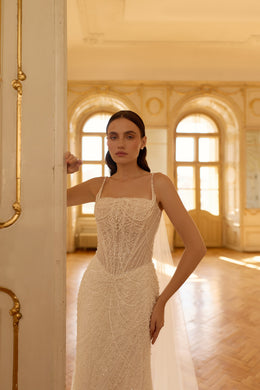 Close-up of intricate beadwork on the square-neck bodice of an ivory wedding dress