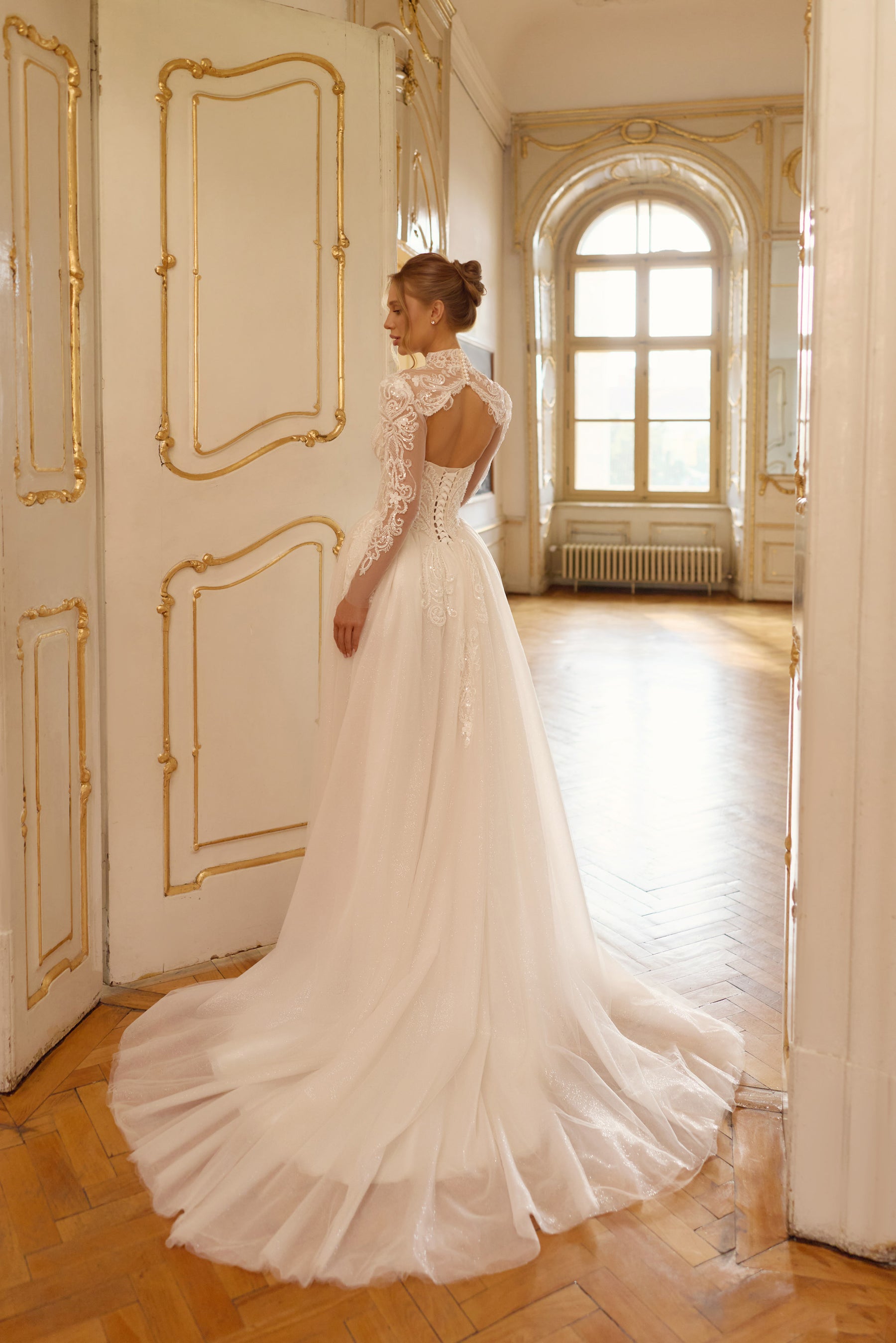 Open-back ivory wedding dress with lace detailing, a sheer high-neck bolero, and a long flowing train
