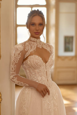 Ivory wedding dress with a high lace neck, long sheer sleeves, sparkling appliqués, and an A-line skirt