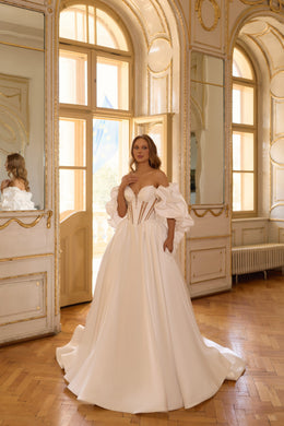 Ivory wedding dress with an off-the-shoulder neckline, puff sleeves, corset bodice, and sweeping ball-gown skirt