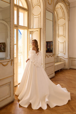Ivory wedding dress shown from the rear with off-the-shoulder puff sleeves and a full skirt flowing into a long train