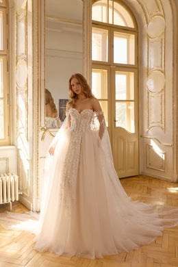 Ivory ball gown wedding dress with an off-the-shoulder lace bodice, sheer sleeves, and a flowing train
